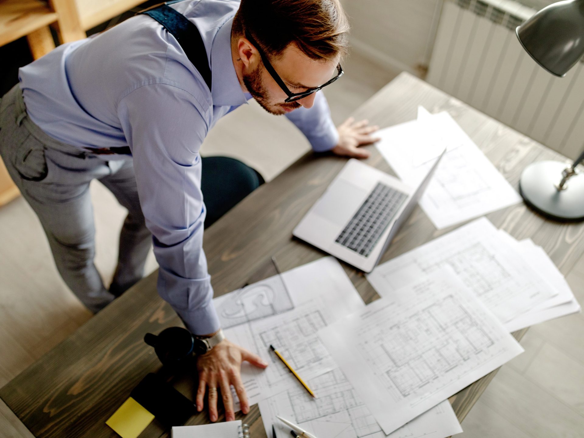 Top view of young architect, thinking about new project, he is lean on the table. Work at home.