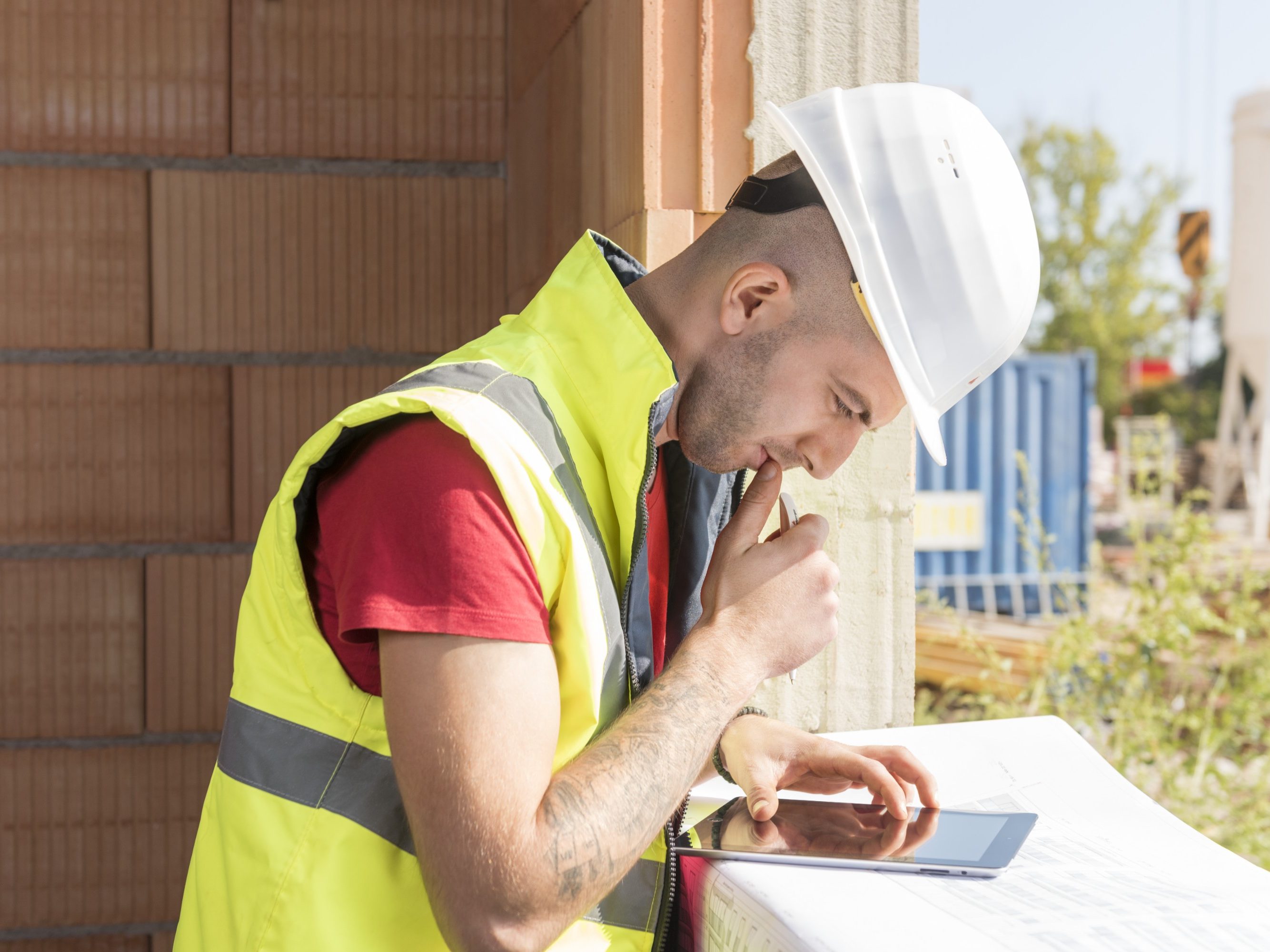 Construction worker working with tablet placed on blueprint in building shell