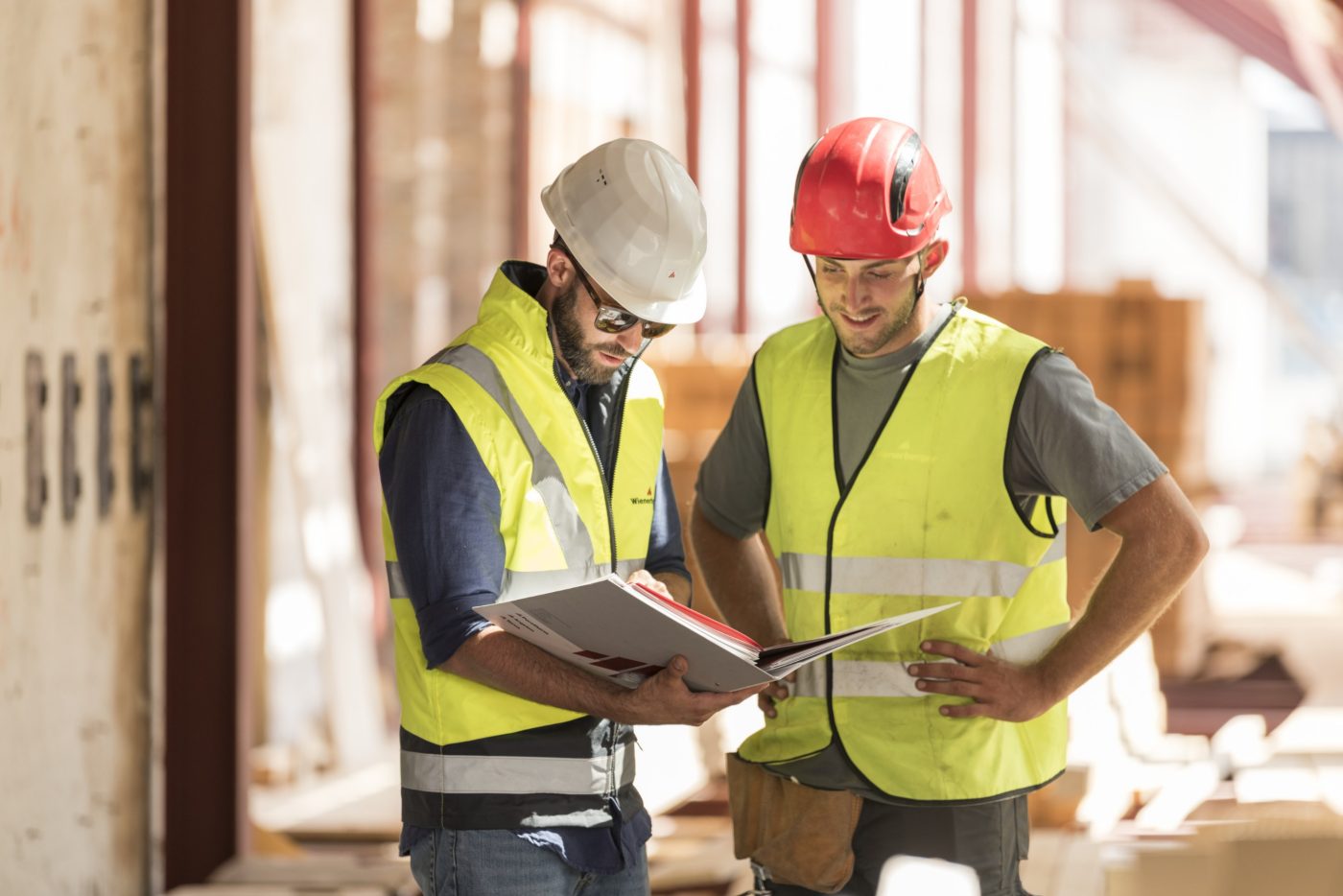 Product manager and roofer talking checking product information in attic under renovation