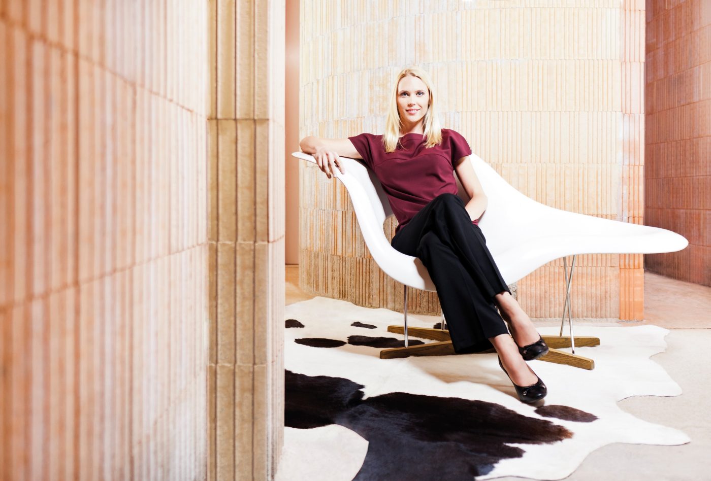 Woman sitting on "La Chaise" Eames chair in unfinished building