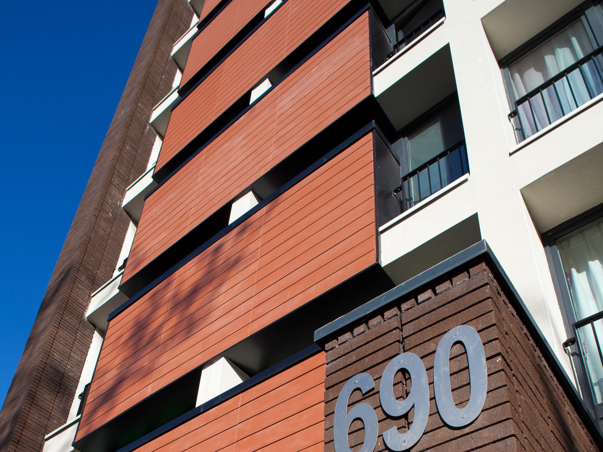 Immeuble avec sept étages de logements collectifs. Mise en œuvre bardage. Brique Terca Brune de wanlin. Panneaux Argeton Bardage Tampa Rouge naturel.