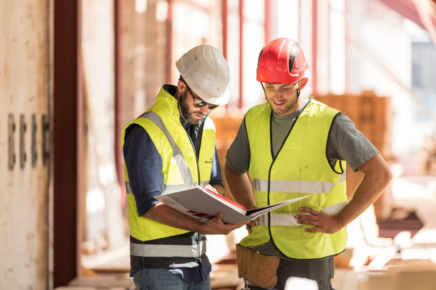 Product manager and roofer talking checking product information in attic under renovation