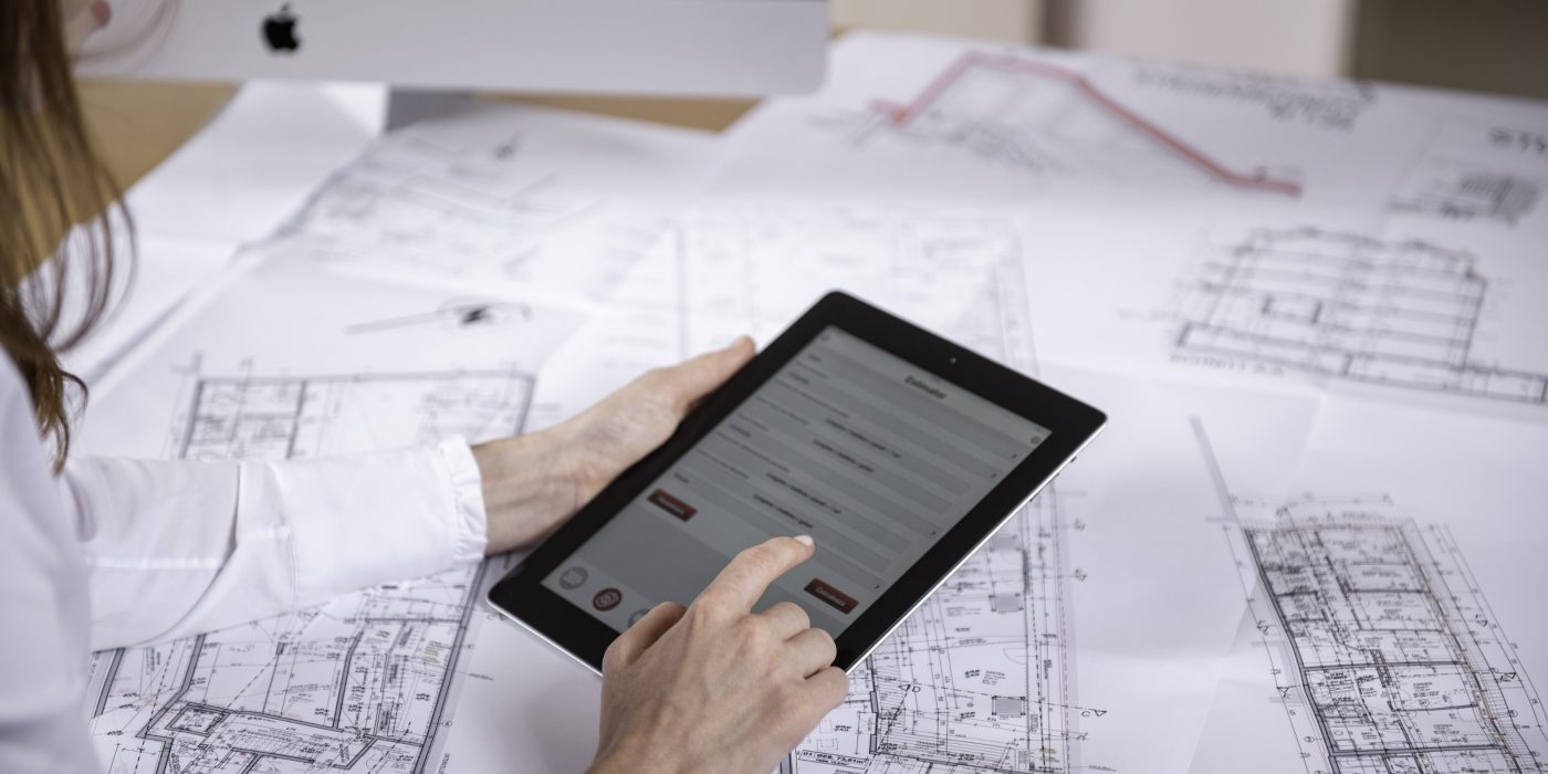 Woman at workplace with blueprint holding tablet computer, Fast Forward Commercial Excellence