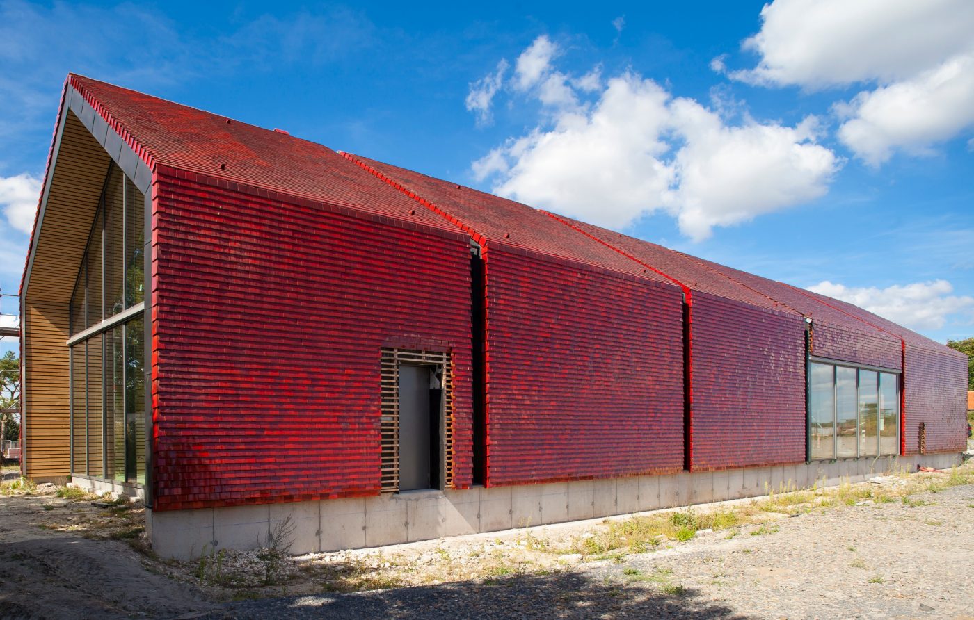 Complexe résidentiel  classé au Patrimoine de l’UNESCO. Aire : 14673 m2. Coût : 9,2 M € HT. Lauréat : Prix du jury au concours d'architecture Bas Carbone EDF & Prix Architecture Bâtiment tertiaire. 62700 BRUAY-LA-BUSSIERE. Tuile Koramic Aléonard Emaillée Rubis. Mise en oeuvre toiture et bardage.