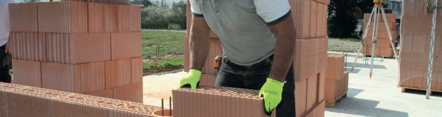 Maçon qui pose une brique en terre cuite Porotherm