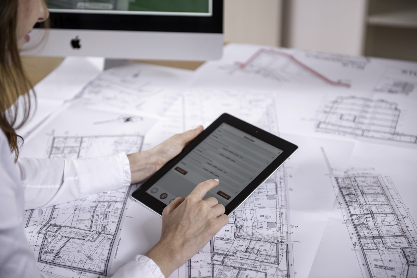 Woman at workplace with blueprint holding tablet computer, Fast Forward Commercial Excellence