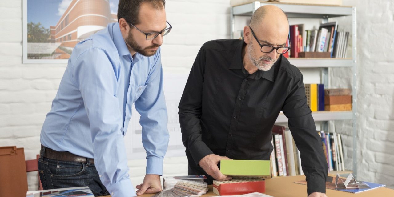 Wienerberger project manager and architect with glazed facing bricks looking at blueprint at architect's office