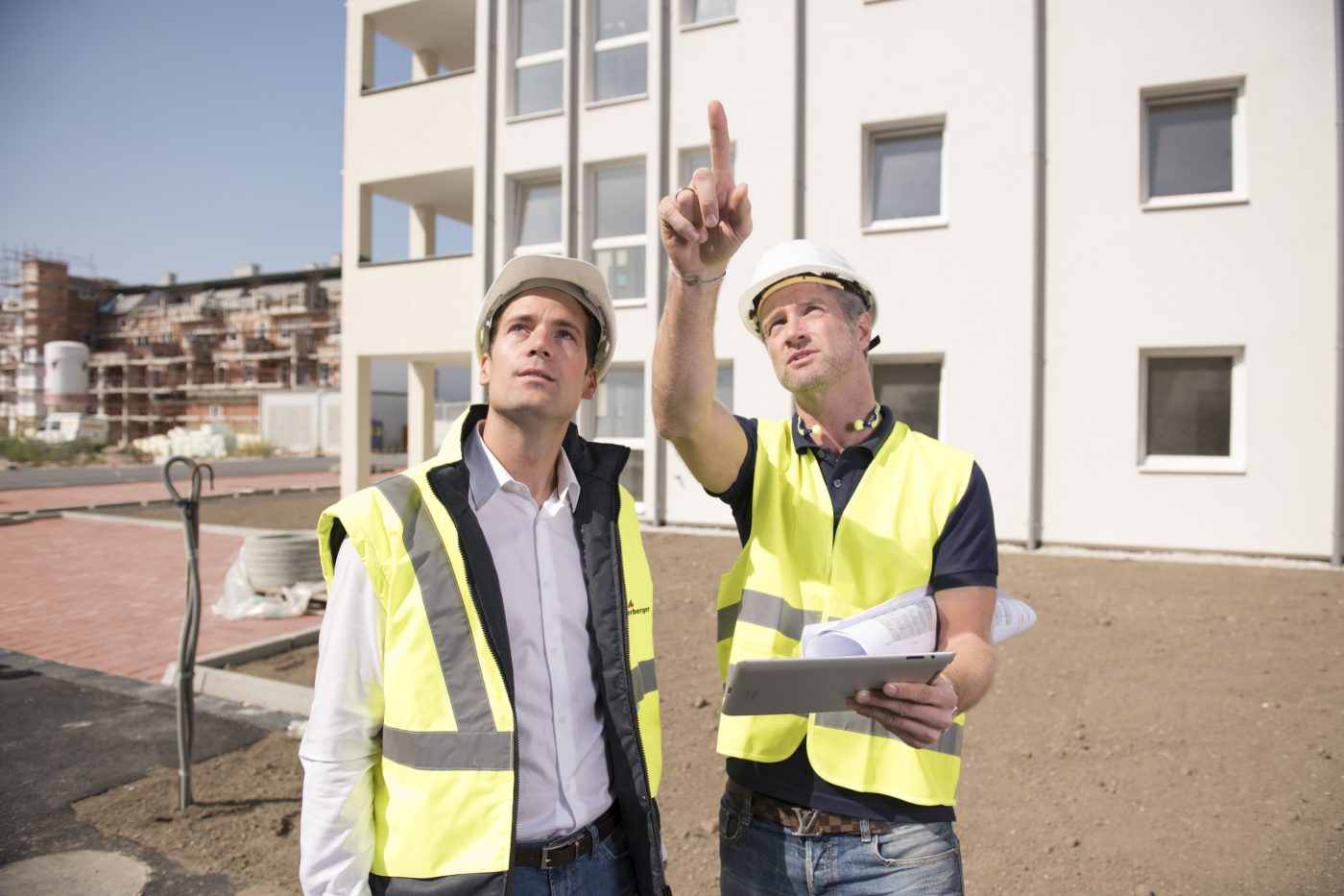 Building professionals monitoring status at construction site holding tablet and pointing finger, Fast Forward Commercial Excellence