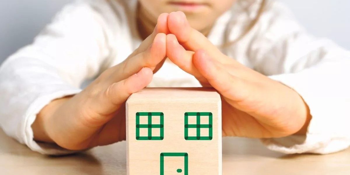 Cube de jeu représentant une maison avec des mains en triangle au dessus
